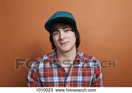 Stock Image - A teenage boy smiling, portrait, studio shot. Fotosearch