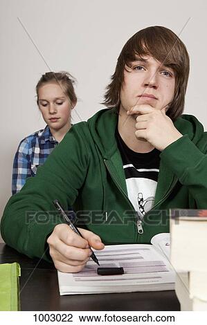 A teenage boy thinking in a classroom, girl in background View Large Photo Image Stock Image - A teenage boy thinking in a classroom, girl in background. Fotosearch