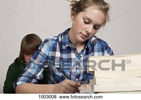 Stock Photo - A teenage girl doing class work, boy in background. Fotosearch