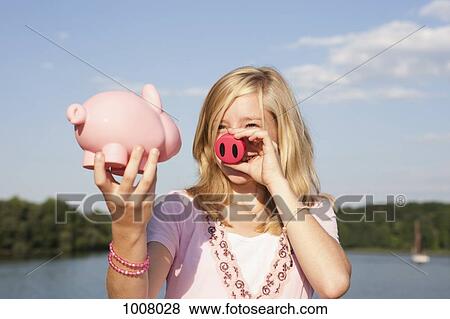 A teenage girl holding a pig nose and a piggy bank View Large Photo Image Stock Photo - A teenage girl holding a pig nose and a piggy bank. Fotosearch