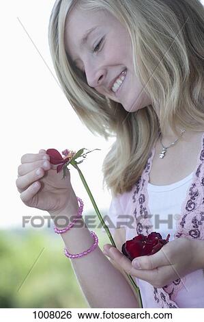 Stock Photograph - A teenage girl picking petals from a flower. Fotosearch