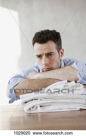 Stock Image - A tired man resting on a stack of folded laundry. Fotosearch