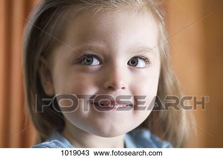Stock Image - A toddler biting her lip and looking contemplative. Fotosearch