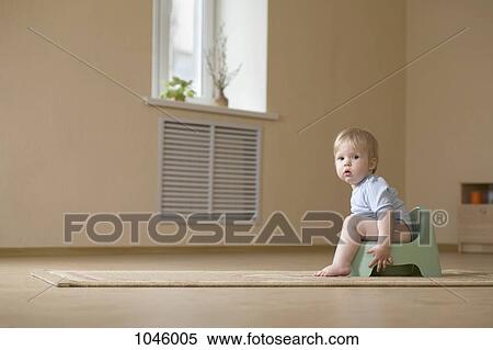 Stock Photography - A toddler sitting on a potty chair, looking at camera. Fotosearch