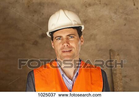 A well-dressed man wearing a hardhat and reflective vest at a building site View Large Photo Image Stock Photo - A well-dressed man wearing a hardhat and reflective vest at a building site. Fotosearch