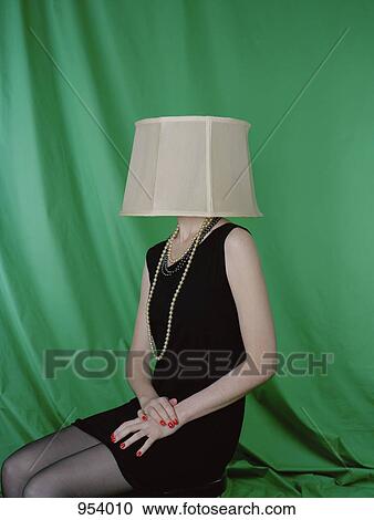 Stock Image - A well-dressed woman wearing a lamp shade on her head. Fotosearch