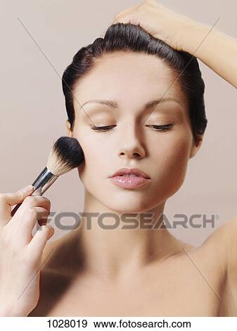 A woman applying blush to her cheek with a make-up brush View Large Photo Image Stock Photo - A woman applying blush to her cheek with a make-up brush. Fotosearch