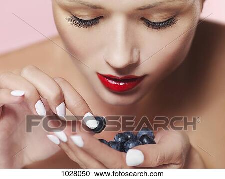 A woman choosing a blueberry from her palm View Large Photo Image Stock Image - A woman choosing a blueberry from her palm. Fotosearch