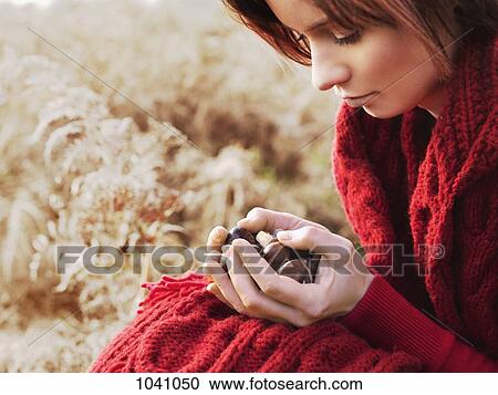 A woman considering a handful of chestnuts she's holding View Large Photo Image Stock Image - A woman considering a handful of chestnuts she's holding. Fotosearch