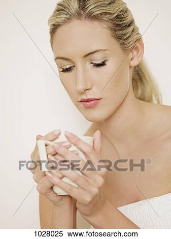 A woman holding a cup and looking serenely into it View Large Photo Image Stock Photography - A woman holding a cup and looking serenely into it. Fotosearch