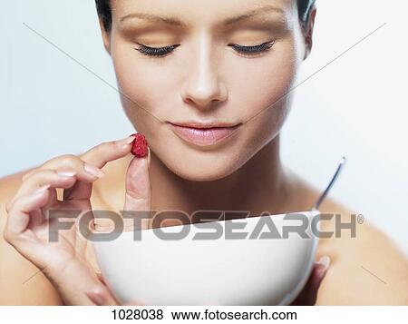 A woman holding a raspberry and looking down into a bowl View Large Photo Image Stock Photo - A woman holding a raspberry and looking down into a bowl. Fotosearch