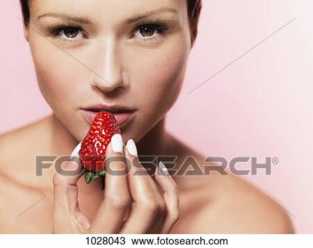 A woman holding a strawberry up to her mouth View Large Photo Image Stock Image - A woman holding a strawberry up to her mouth. Fotosearch