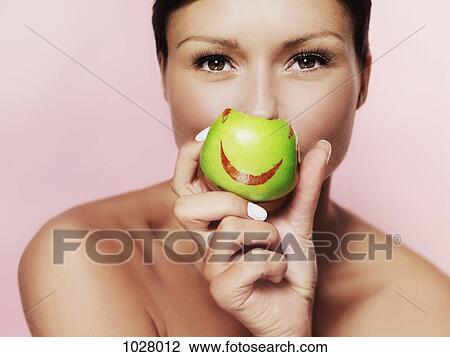 A woman holding up a green apple with bright red lipstick on it View Large Photo Image Stock Image - A woman holding up a green apple with bright red lipstick on it. Fotosearch