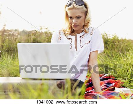 A woman in nature using a laptop View Large Photo Image Stock Image - A woman in nature using a laptop. Fotosearch