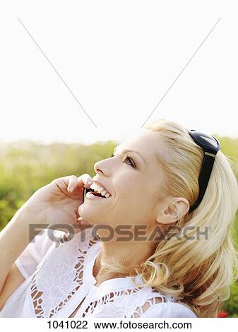 A woman in nature using a mobile phone and laughing View Large Photo Image Stock Image - A woman in nature using a mobile phone and laughing. Fotosearch
