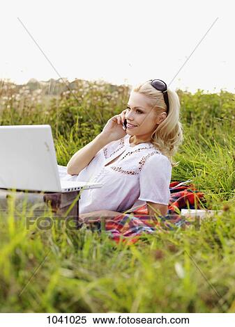 A woman in nature with an open laptop and using a mobile phone View Large Photo Image Stock Photography - A woman in nature with an open laptop and using a mobile phone . Fotosearch