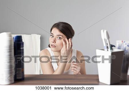 Stock Image - A woman inspecting her face . Fotosearch
