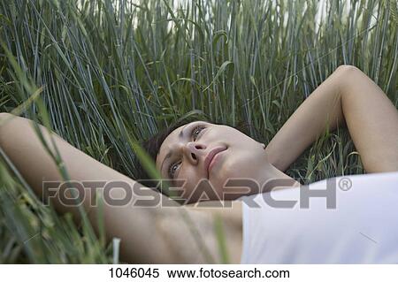 A woman lying in grass, day dreaming View Large Photo Image Stock Photography - A woman lying in grass, day dreaming. Fotosearch