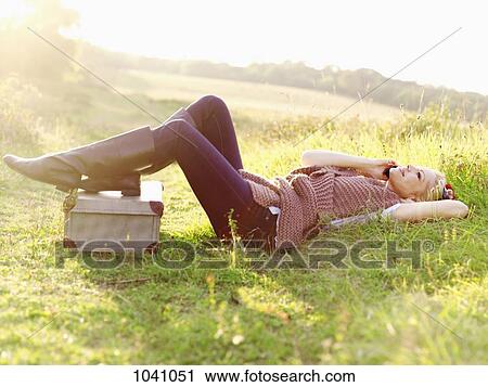 A woman lying in grass using a mobile phone View Large Photo Image Stock Image - A woman lying in grass using a mobile phone. Fotosearch