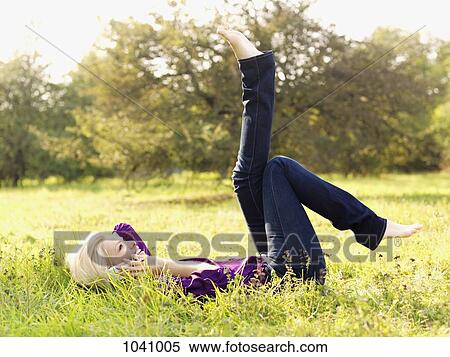 A woman lying on her back with her legs raised using a mobile phone View Large Photo Image Stock Photography - A woman lying on her back with her legs raised using a mobile phone. Fotosearch