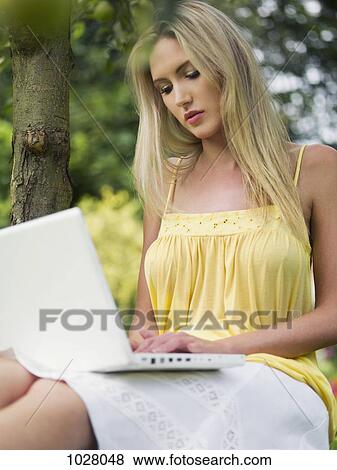 A woman outdoors in summer using a laptop View Large Photo Image Stock Photo - A woman outdoors in summer using a laptop. Fotosearch