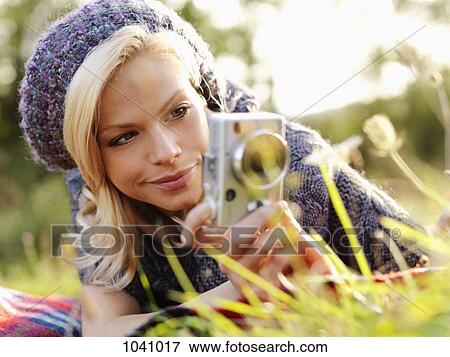 A woman photographing while lying in grass View Large Photo Image Stock Photo - A woman photographing while lying in grass. Fotosearch