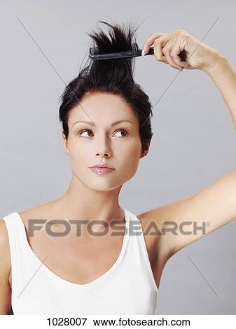 A woman playfully combing her hair View Large Photo Image Stock Photo - A woman playfully combing her hair. Fotosearch