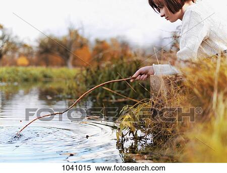 A woman poking at the water with a stick View Large Photo Image Stock Photography - A woman poking at the water with a stick. Fotosearch