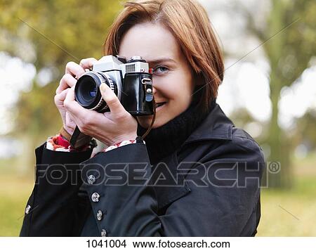 A woman preparing to take a photograph, outdoors, head and shoulders View Large Photo Image Picture - A woman preparing to take a photograph, outdoors, head and shoulders. Fotosearch