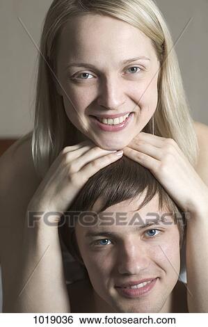 Stock Photograph - A woman resting her chin on top of her boyfriend's head, portrait. Fotosearch