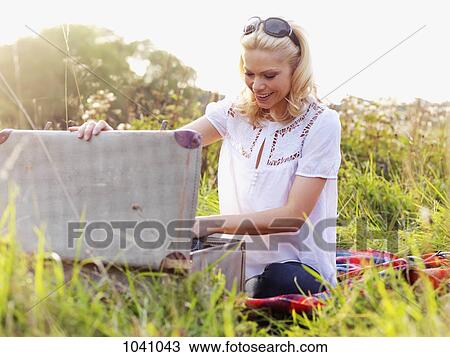 A woman sitting in the grass rummaging through an open suitcase View Large Photo Image Stock Image - A woman sitting in the grass rummaging through an open suitcase. Fotosearch