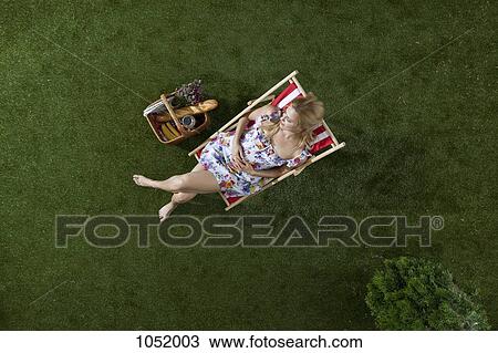 A woman sitting in the sun on a grass in a park with a picnic basket, overhead view View Large Photo Image Stock Image - A woman sitting in the sun on a grass in a park with a picnic basket, overhead view. Fotosearch