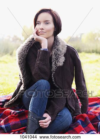 A woman sitting on a blanket and looking away, outdoors View Large Photo Image Picture - A woman sitting on a blanket and looking away, outdoors. Fotosearch