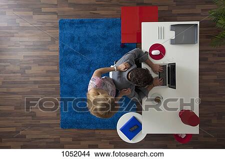 A woman standing behind her man while he works in his home office, overhead view View Large Photo Image Picture - A woman standing behind her man while he works in his home office, overhead view. Fotosearch