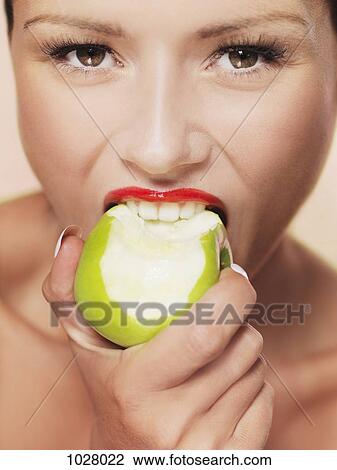 A woman taking a bite out of a green apple View Large Photo Image Stock Image - A woman taking a bite out of a green apple. Fotosearch