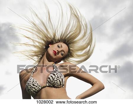 Stock Image - A woman wearing a bikini toss her hair. Fotosearch