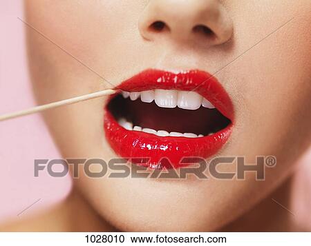 A woman with bright red lipstick on using a toothpick View Large Photo Image Stock Image - A woman with bright red lipstick on using a toothpick. Fotosearch