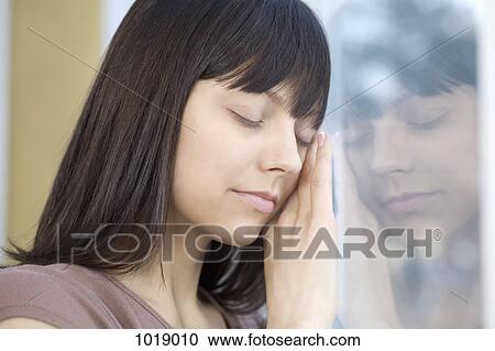 A woman with her eyes closed leaning against a window View Large Photo Image Stock Image - A woman with her eyes closed leaning against a window. Fotosearch