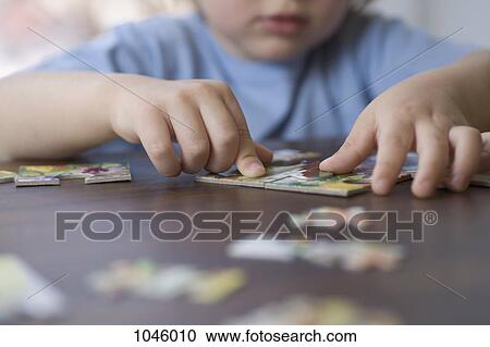 A young boy doing a jigsaw puzzle, focus on hands View Large Photo Image Stock Image - A young boy doing a jigsaw puzzle, focus on hands. Fotosearch
