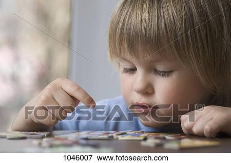 A young boy putting together a puzzle View Large Photo Image Stock Photo - A young boy putting together a puzzle. Fotosearch