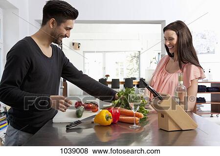 A young couple preparing food together in a modern apartment View Large Photo Image Stock Photo - A young couple preparing food together in a modern apartment. Fotosearch