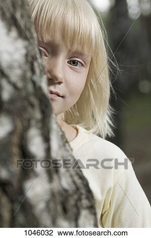 A young girl behind a tree, peeking around it View Large Photo Image Stock Image - A young girl behind a tree, peeking around it. Fotosearch