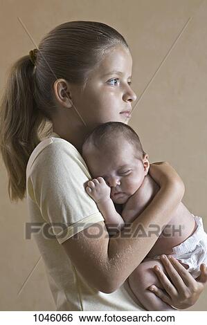 A young girl holding her baby sister closely View Large Photo Image Stock Photograph - A young girl holding her baby sister closely. Fotosearch