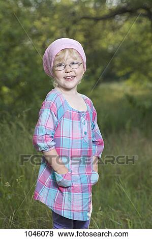 A young smiling girl with her hands in her pockets standing in nature View Large Photo Image Stock Photo - A young smiling girl with her hands in her pockets standing in nature. Fotosearch