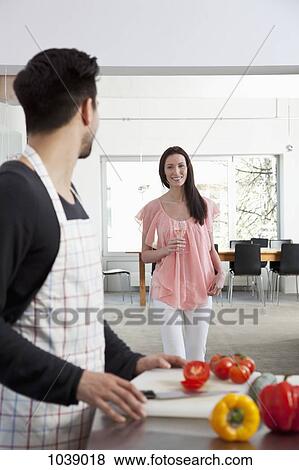 A young woman drinking wine while her boyfriend cooks, focus on woman View Large Photo Image Stock Photo - A young woman drinking wine while her boyfriend cooks, focus on woman. Fotosearch