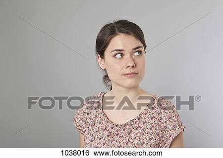 Stock Photograph - A young woman looking up and to the side. Fotosearch