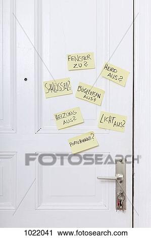Stock Image - Adhesive notes on a front door with various reminders in German. Fotosearch