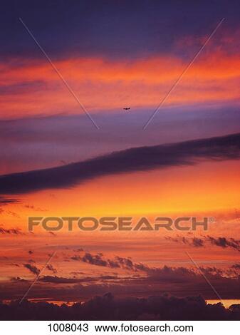 An airplane flying in the sky as the sun sets View Large Photo Image Stock Image - An airplane flying in the sky as the sun sets. Fotosearch