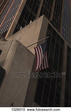 Stock Image - An American flag hanging from a skyscraper, Manhattan. Fotosearch