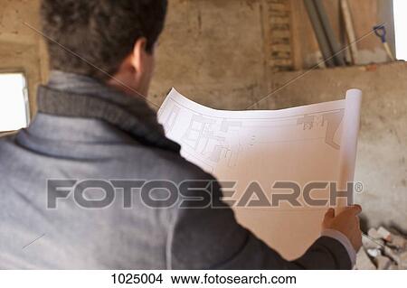 Picture - An architect reviewing blueprints at a building site. Fotosearch